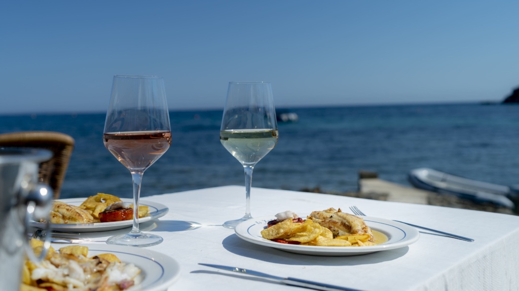 Mesa del restaurante Es Xarcu con platos de pescado y vistas al mar
